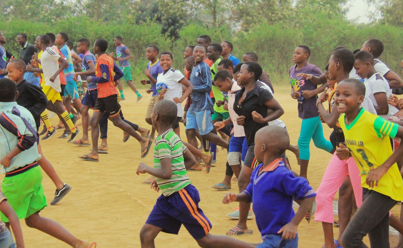 Rennende Schulkinder in Muyange, Ruanda. Mit jeder Kakaobaum-Patenschaft unterstützt du den Bau eines Mädchenhauses!